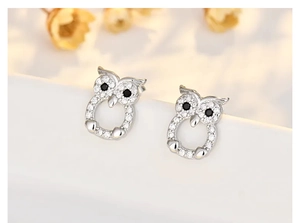 Detailed view of silver owl stud earrings with sparkling white and black cubic zirconia