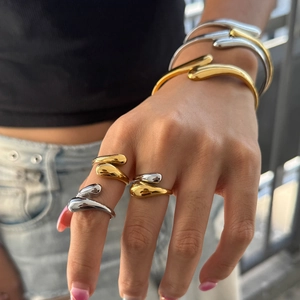 Polished liquid metal rings and open cuffs set in gold and silver finish on model