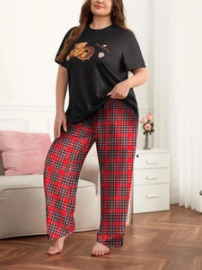 Dettaglio dei pantaloni rossi a quadri e t-shirt nera con orso fragola sul pigiama