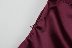Detailed close-up of a concealed side zipper on a burgundy satin sleeveless dress