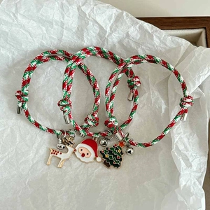 Close-up of Christmas braided rope bracelets with deer, Santa, and tree enamel charms