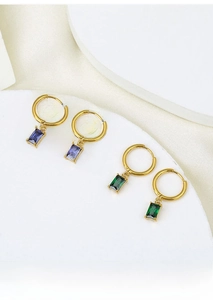 Detail view of gold square hoop earrings with purple and green zircon gemstones