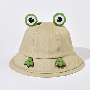 Détail du chapeau bob kaki avec yeux de grenouille 3D et broderie 'Good' sur le bord