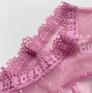 Détail de la dentelle rose avec bords pétales et texture résille à pois de la culotte