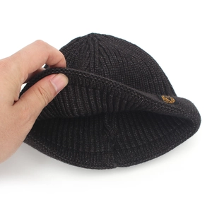 Men's black ribbed knit beanie with orange gold embroidery badge for winter warmth