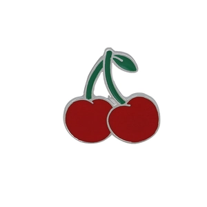 Detail of red cherry enamel brooch with green leaves and polished silver metal edges
