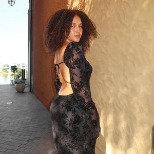 Detail view of backless black floral print dress featuring long sleeves and sleek bodycon fit