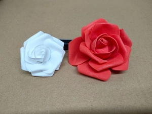 Close-up of artificial foam rose hair clips in red and white on a rustic paper background
