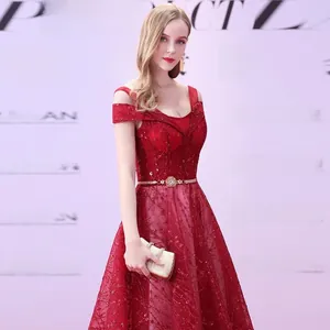 Detail of dark red sequin evening dress with off-shoulder straps and golden waist belt