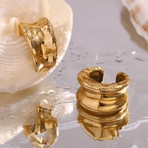 Vue macro d'un earcuff en acier inoxydable plaqué or 18K avec texture concave et gouttes d'eau