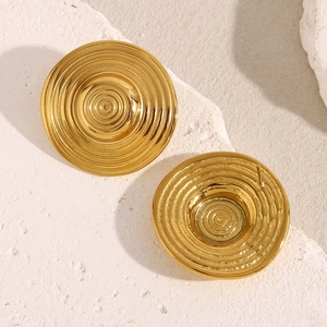 Detailed view of 18K gold plated concentric circle earrings on a textured stone
