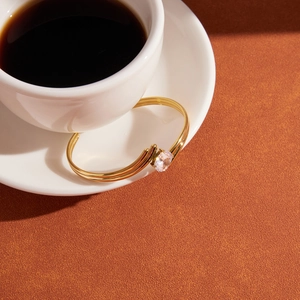 Golden titanium steel open bangle with sparkling cubic zirconia on a coffee table set
