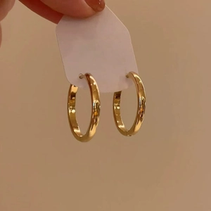 Close-up of classic golden hoop earrings on a display card held in hand