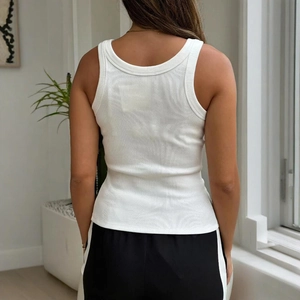 Rear view of white ribbed knit tank top with racerback cut on model in a bright room