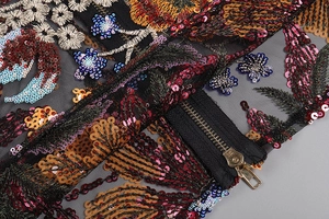 Close-up of floral embroidery with sequins and metal zipper on black mesh dress