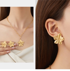 Detail of vintage gold flower jewelry set with radial brushed texture and petal design