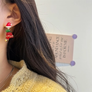 Detail of beaded Christmas hat and bell earrings worn by a model in a festive style