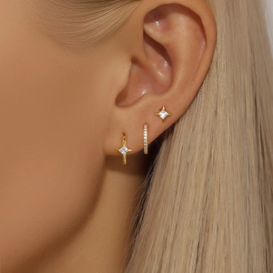 Close-up of star-shaped gold earrings set with sparkling zircons on female model