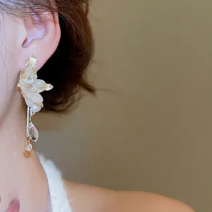 Elegant gold butterfly wing earrings with freshwater pearls and tassels worn by a model