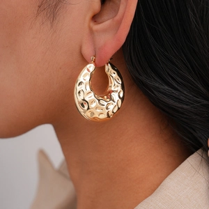Close-up of chunky gold hammered hoop earrings featuring vintage textured metal finish