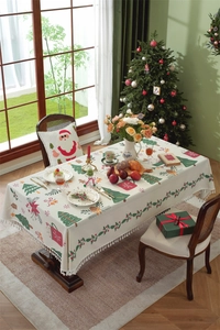 Detailed view of beige Christmas tablecloth with festive prints and fringe on wood table