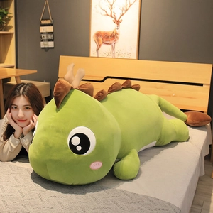 Large green dinosaur plush toy pillow in a lying position on a bed for home decor