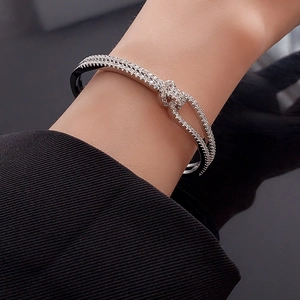 Detail of silver double-layer knot bracelet with zircon inlay on woman's wrist