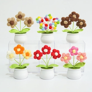 Row of colorful handmade knitted lily of the valley flowers in white ceramic pots