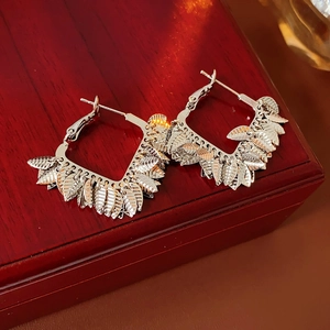 Detail view of silver feather hoop earrings with fine texture on a wooden gift box