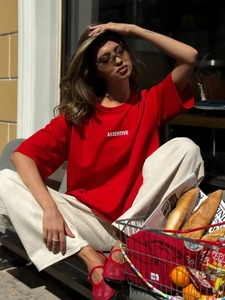 Dettaglio di una t-shirt rossa in cotone con stampa Assertive bianca sul petto