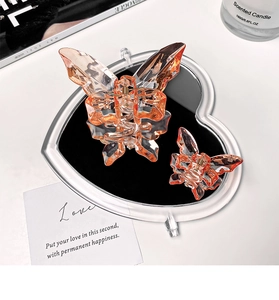 Close-up of orange transparent butterfly hair clips on a heart-shaped mirror tray