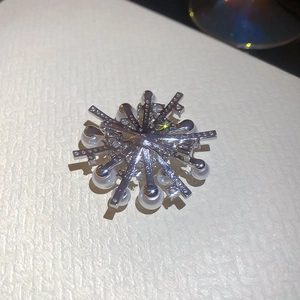 Detailed macro view of silver starburst brooch with white pearls and sparkling cubic zirconia