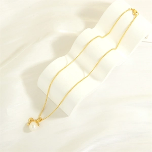 Detail of gold bow pendant necklace with freshwater pearl and sparkling crystals