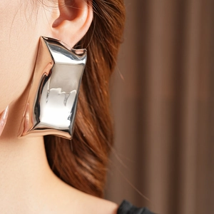 Gros plan de boucles d'oreilles rectangulaires en métal argenté à l'effet froissé