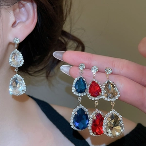 Detail of drop-shaped crystal earrings in blue, red, gold, and white with diamond pavé