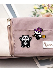 Detailed view of Halloween panda enamel pins with skeleton and witch hat on a canvas bag
