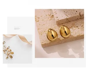 Close-up of golden teardrop earrings with a mirror finish on a stone surface