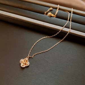 Detail of rose gold clover necklace with zircon diamonds on a brown jewelry box