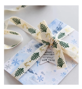 Detail of Christmas ribbon with green trees and gold Joy text on a gift package