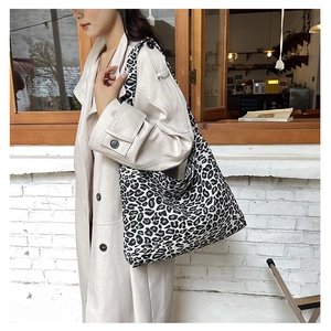 Stylishly large leopard print tote bag worn with a classic beige trench coat outdoors