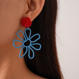 Gros plan d'un mannequin portant des boucles d'oreilles en résine à fleurs rouge et bleu