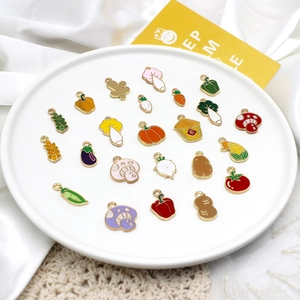 Close-up of colorful enamel vegetable charms like chili and carrot in a white dish