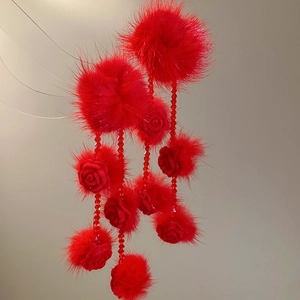Detail of red plush fur ball earrings with crystal tassels and rose floral design