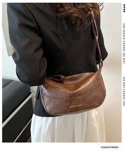 Dettaglio borsa a mezzaluna marrone vintage con tracolla regolabile e logo dorato