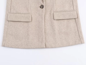 Close-up of oatmeal blazer featuring soft wool texture, flap pockets, and button detail
