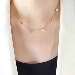Elegant gold choker necklace with heart charms and zircon stones on a female model