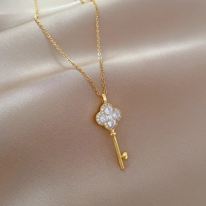 Elegant gold clover key necklace with sparkling crystals on a beige satin background