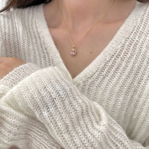 Detail of a 925 sterling silver gold necklace with pink zircon pendant on a white sweater