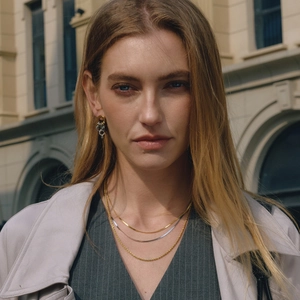 Chic layered gold snake and twisted chain necklace with matching hoop earrings on a model