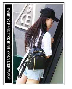 Outdoor view of a black nylon backpack with gold zippers and multi-pocket design
